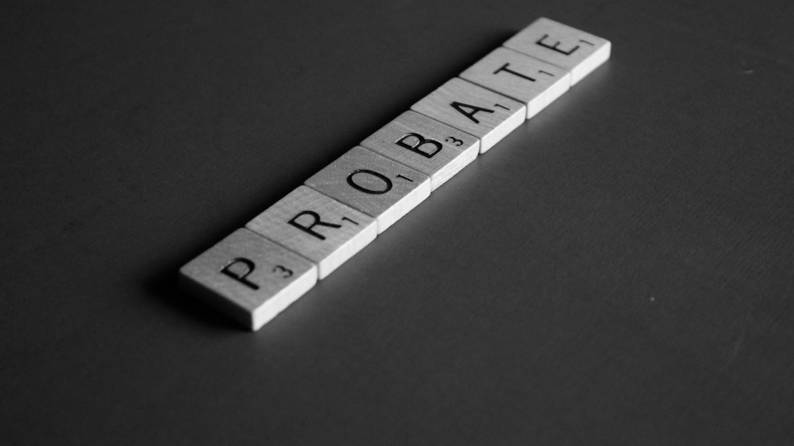 Scrabble tiles spelling the word “Probate” on a gray surface.