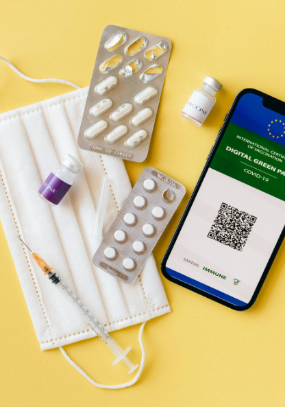 This image shows a white mask, medicines, an injection, and a mobile.