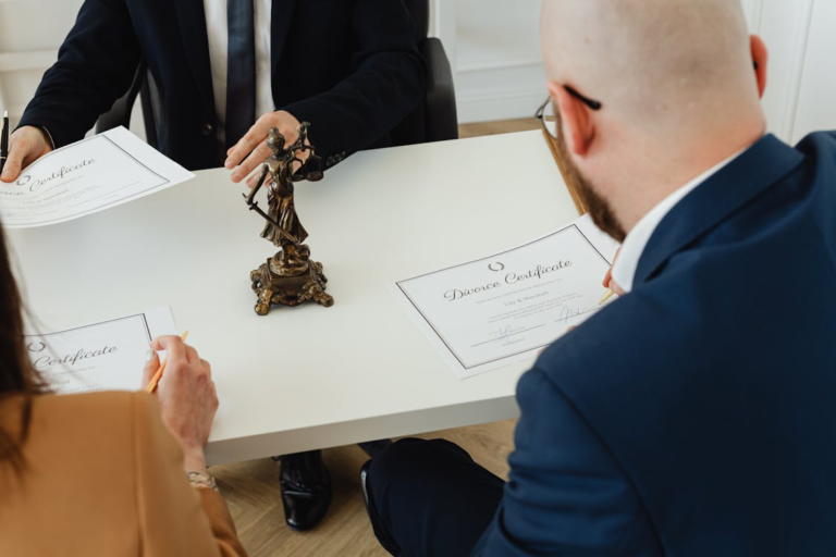 people signing divorce certificates at a lawyer's office with a lady justice figurine on the table