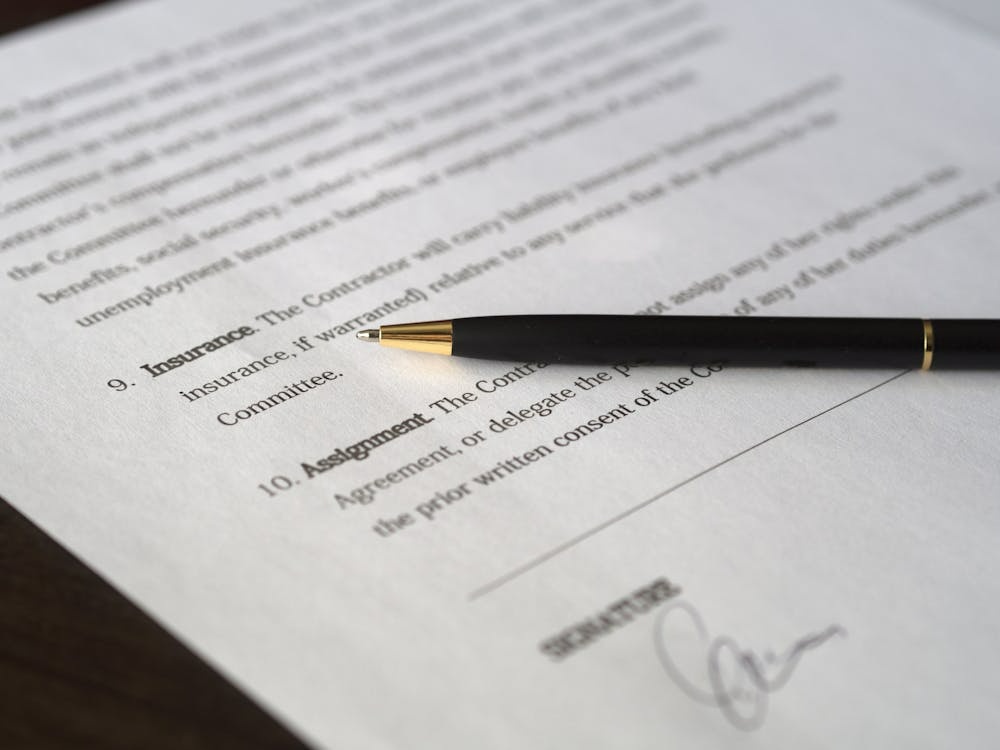 Pen resting on a signed legal document on a wooden desk