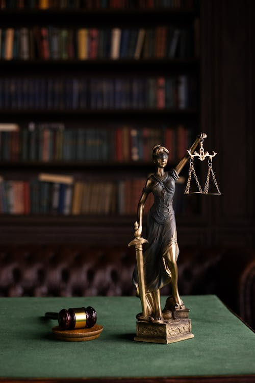 Lady Justice statue and gavel in a classic law library setting