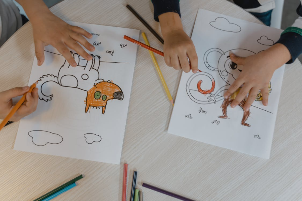 Colorful children's drawings and a set of colored pencils arranged on a wooden table