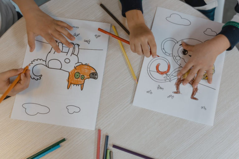 Colorful children's drawings and a set of colored pencils arranged on a wooden table