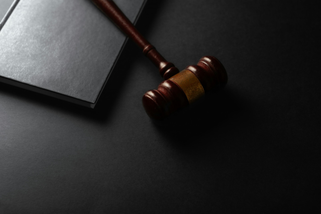 A wooden gavel resting on a dark surface next to a book