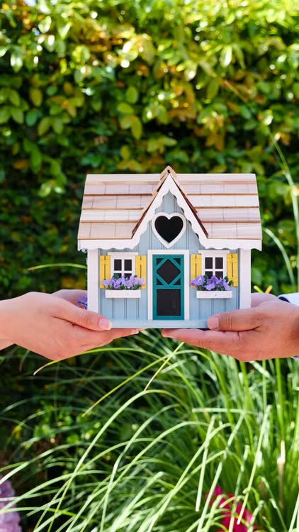 An image of two people holding a miniature house