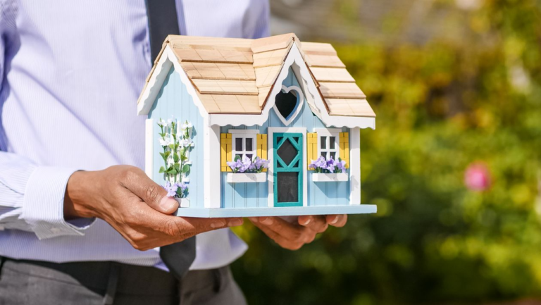 An image of a person holding a miniature house