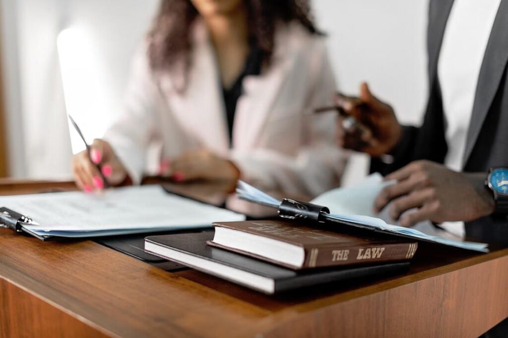 An image of people standing at a podium with law books laced on top of it