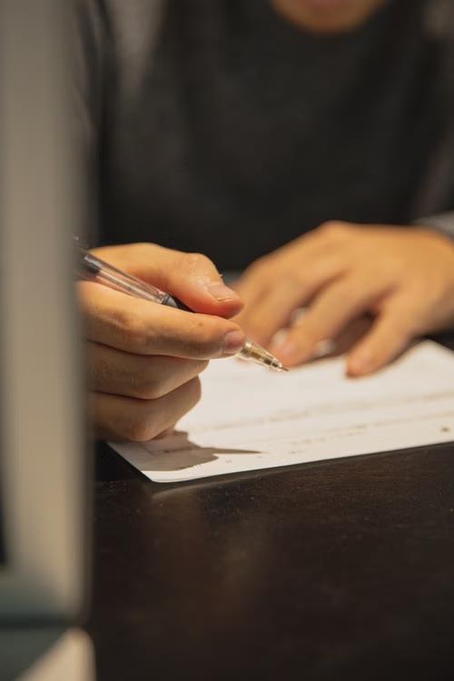 An imageof a person holding a pen over a document