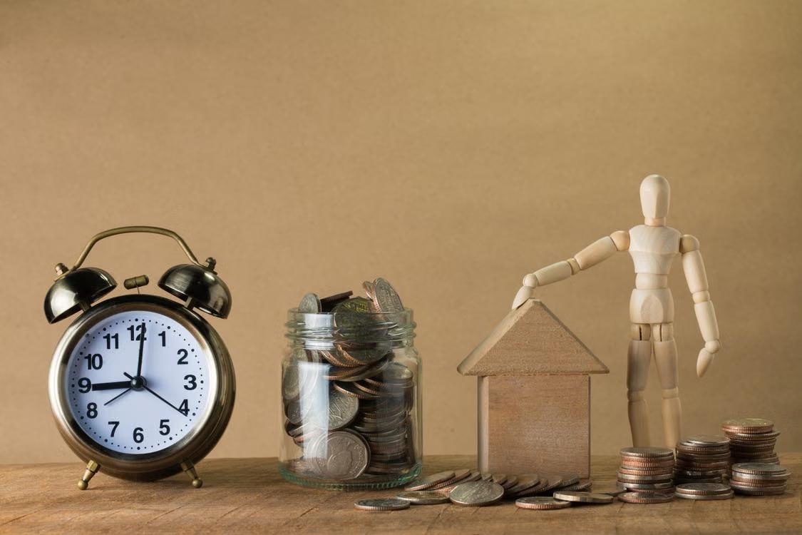 An image of wooden items beside a clock and a jar of coins