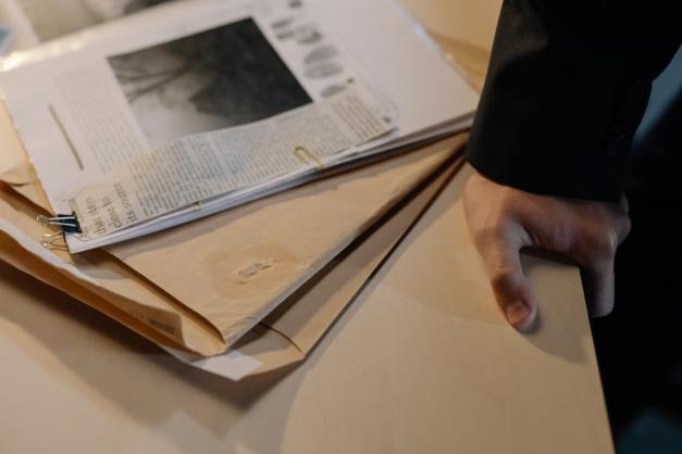 An image of a person holding onto a desk with documents on it