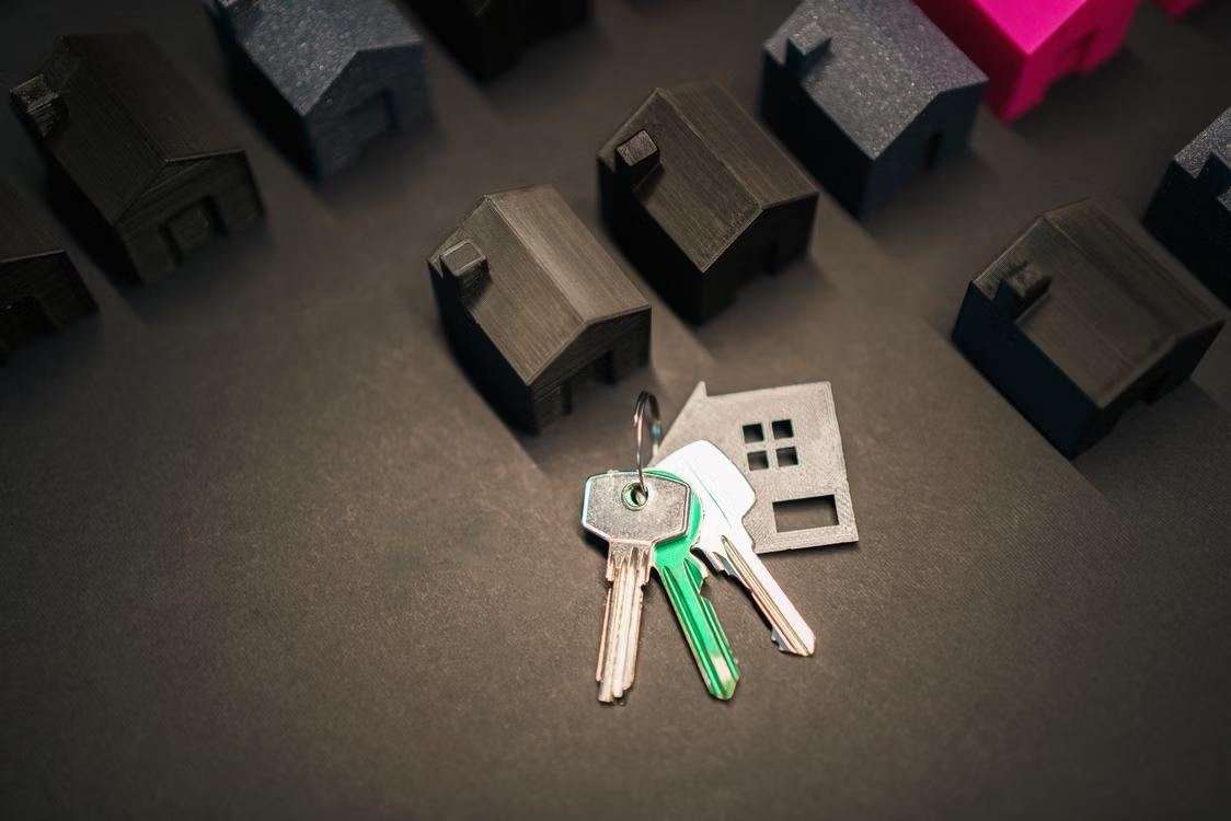 Miniature houses and keys arranged on a dark surface