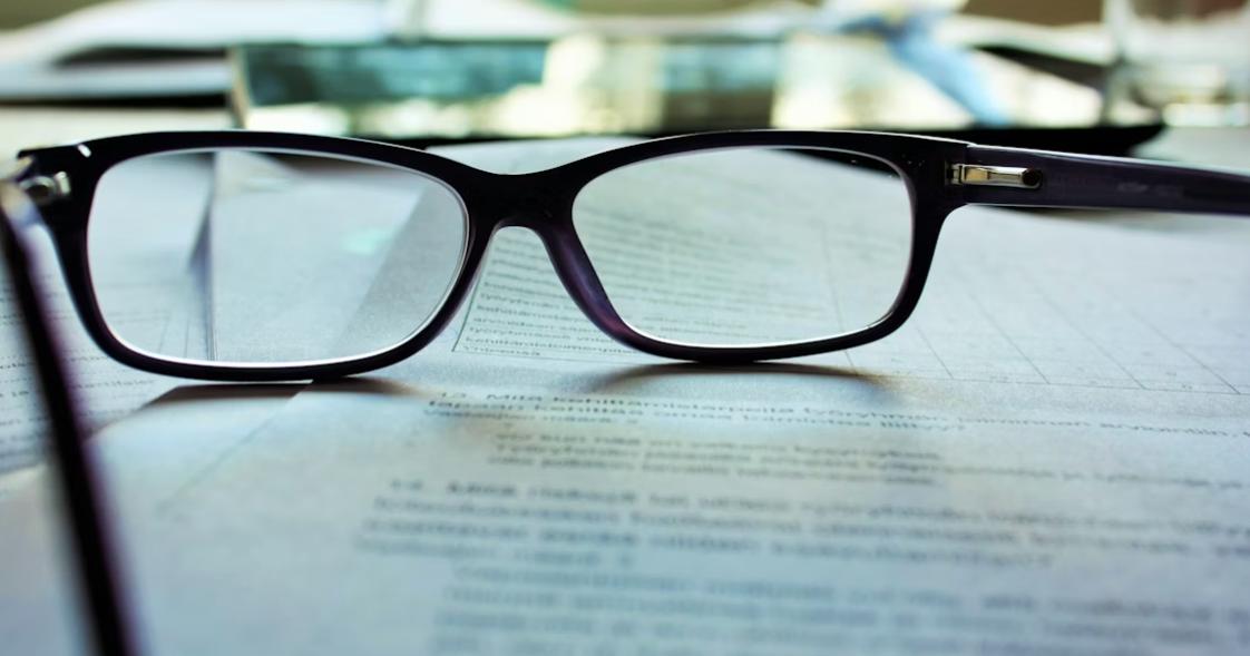 Black-framed eyeglasses resting on a printed document