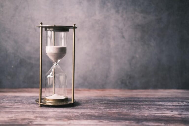 Sandglass on a wooden table against a gray wall
