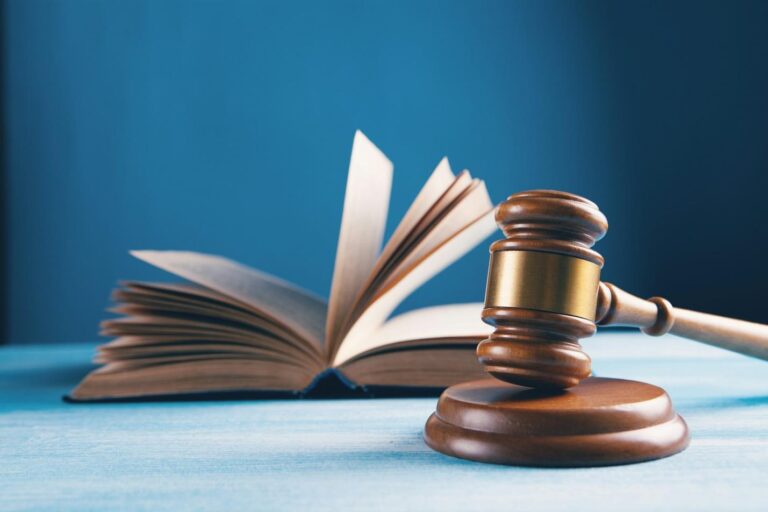 Wooden gavel resting beside an open book on a blue table